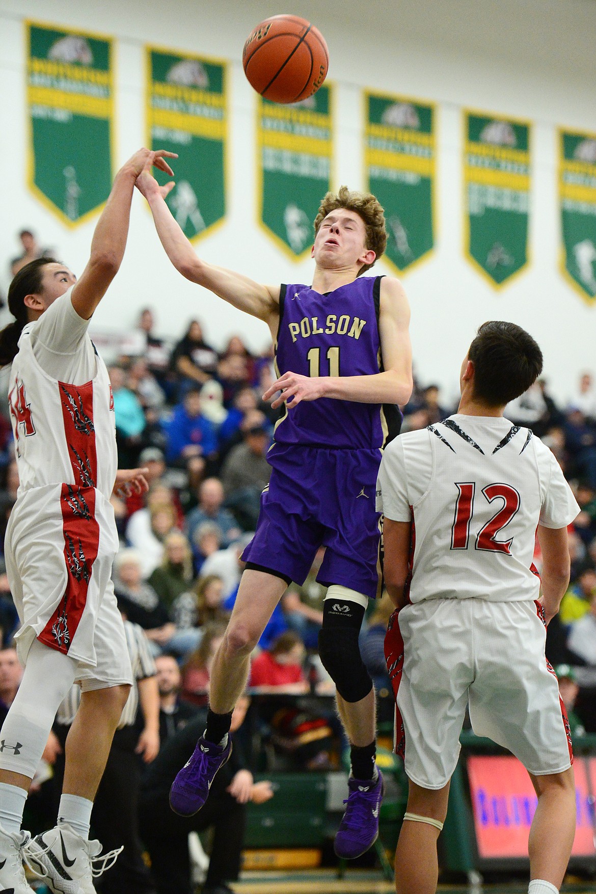 Polson's Robin Erickson (11) drives to the basket between Browning defenders Deion Mad Plume (34) and Ethan Running Crane (12) during the Northwest A District boys' championship game at Whitefish High School on Saturday. Browning won, 78-50. (Casey Kreider/Daily Inter Lake)