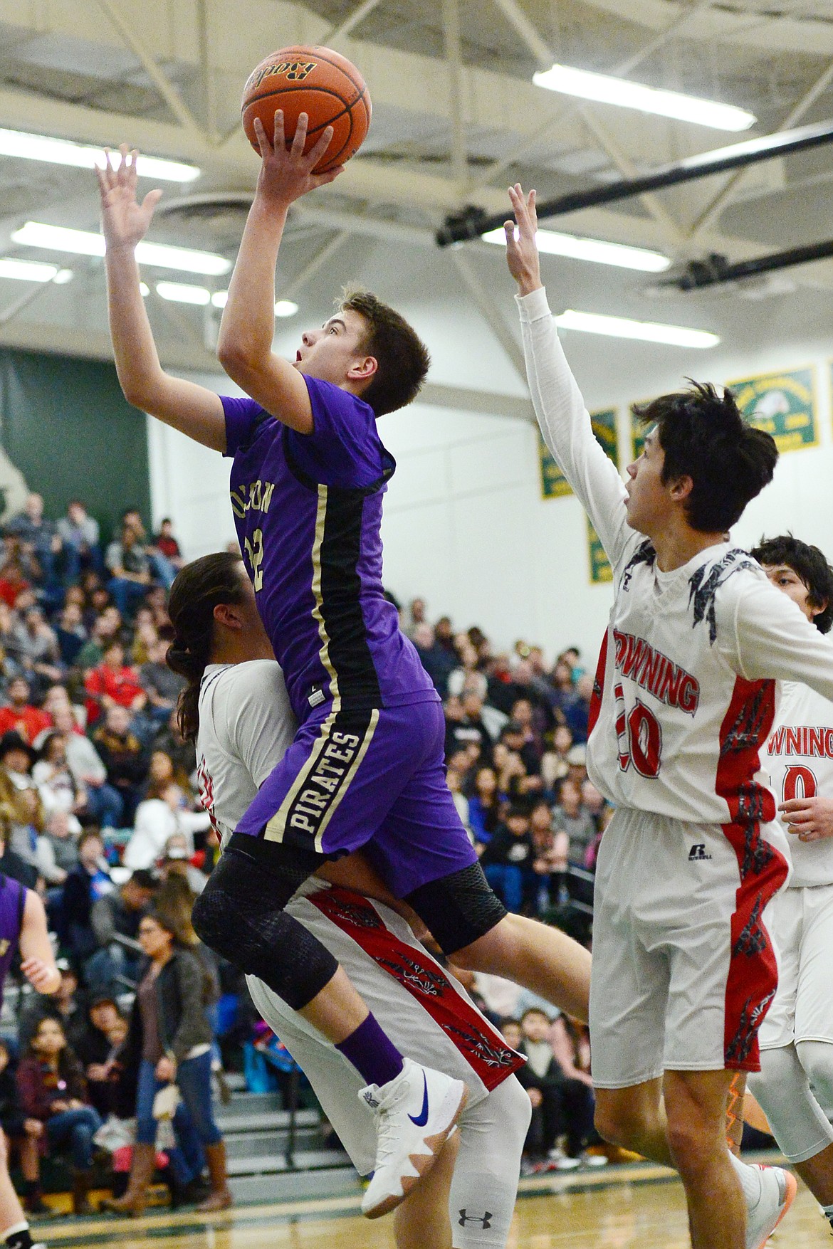 Polson's Colton Graham (32) drives to the hoop against Browning's Deion Mad Plume (34) and CJ Smith (20) during the Northwest A District boys' championship game at Whitefish High School on Saturday. Browning won, 78-50. (Casey Kreider/Daily Inter Lake)