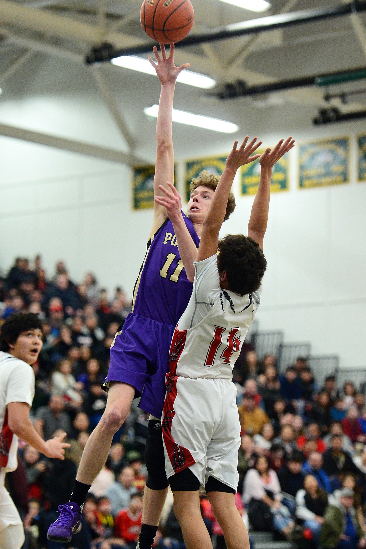 Polson's Robin Erickson (11) releases a shot in the lane over Browning's Derek Sharp (14) during the Northwest A District boys' championship game at Whitefish High School on Saturday. Browning won, 78-50. (Casey Kreider/Daily Inter Lake)