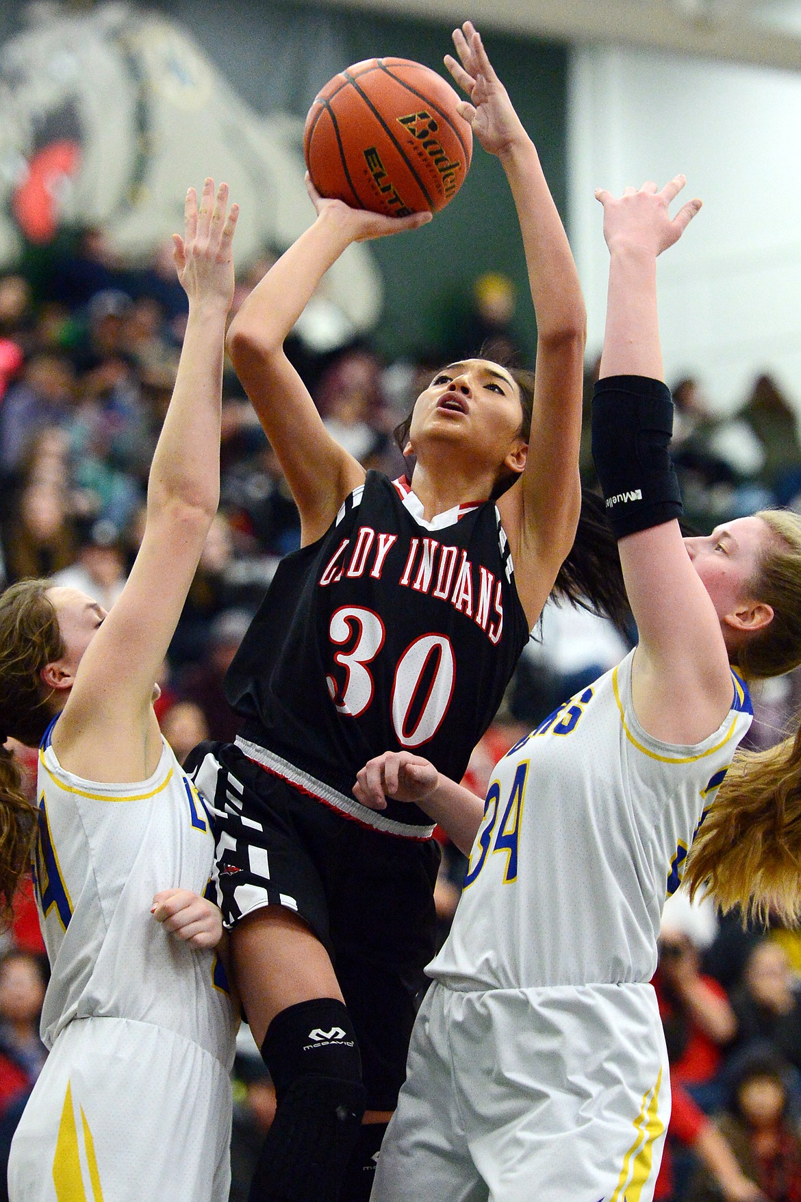 Browning's Dulci Skunkcap (30) drives to the hoop between Libby defenders Jayden Winslow (24) and McKenzie Proffitt (34) at Whitefish High School on Friday. (Casey Kreider/Daily Inter Lake)