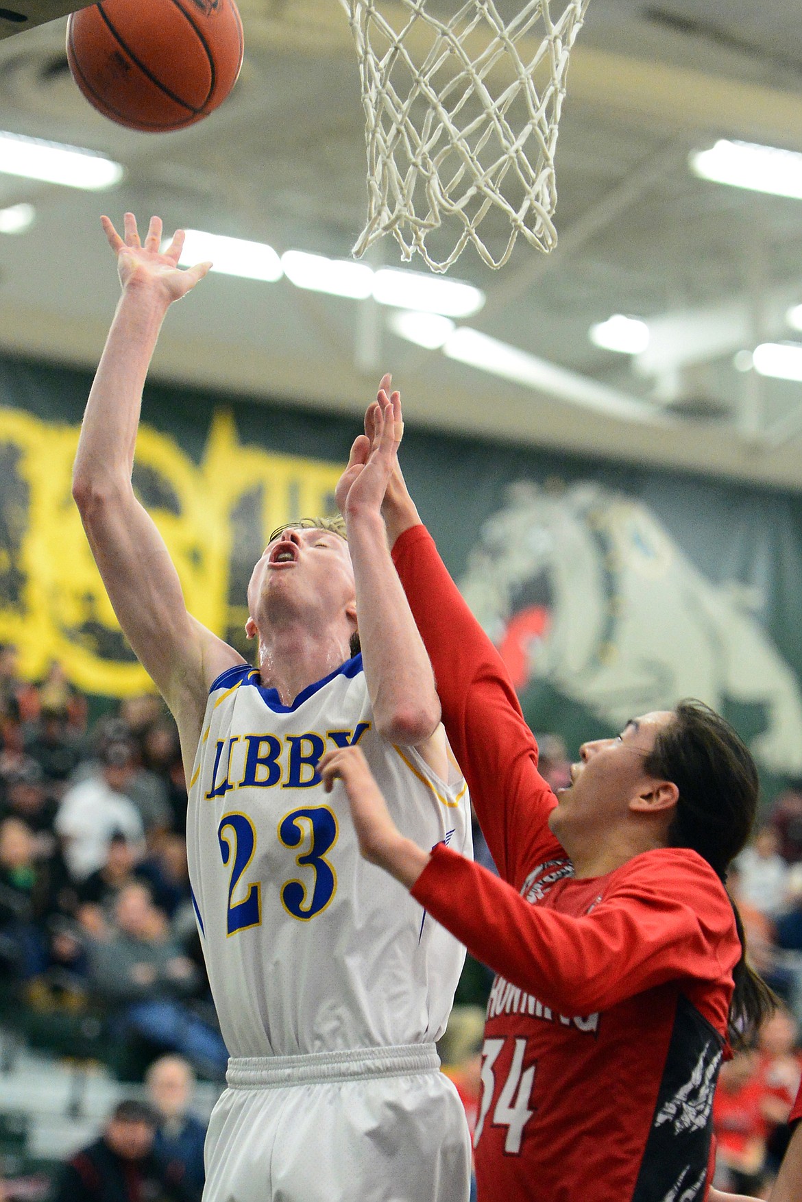 Libby's Ryggs Johnston (23) is fouled at the basket by Browning's Deion Mad Plume (34) at Whitefish High School on Friday. (Casey Kreider/Daily Inter Lake)