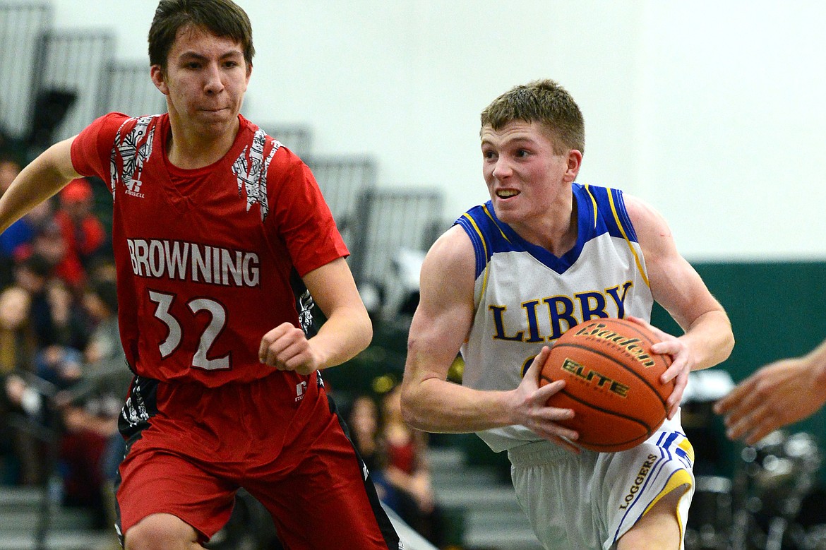 Libby's Jay Beagle (24) drives to the hoop past Browning's Justin Burd (32) at Whitefish High School on Friday. (Casey Kreider/Daily Inter Lake)