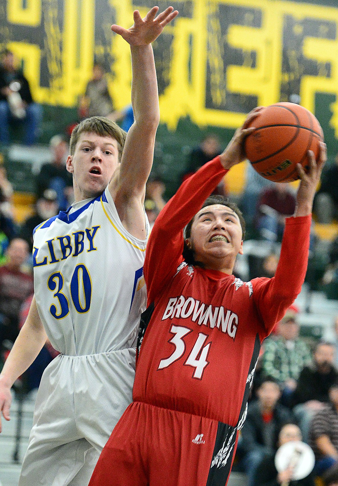 Browning's Deion Mad Plume (34) drives to the hoop in front of Libby's Caden Williams (30) at Whitefish High School on Friday. (Casey Kreider/Daily Inter Lake)