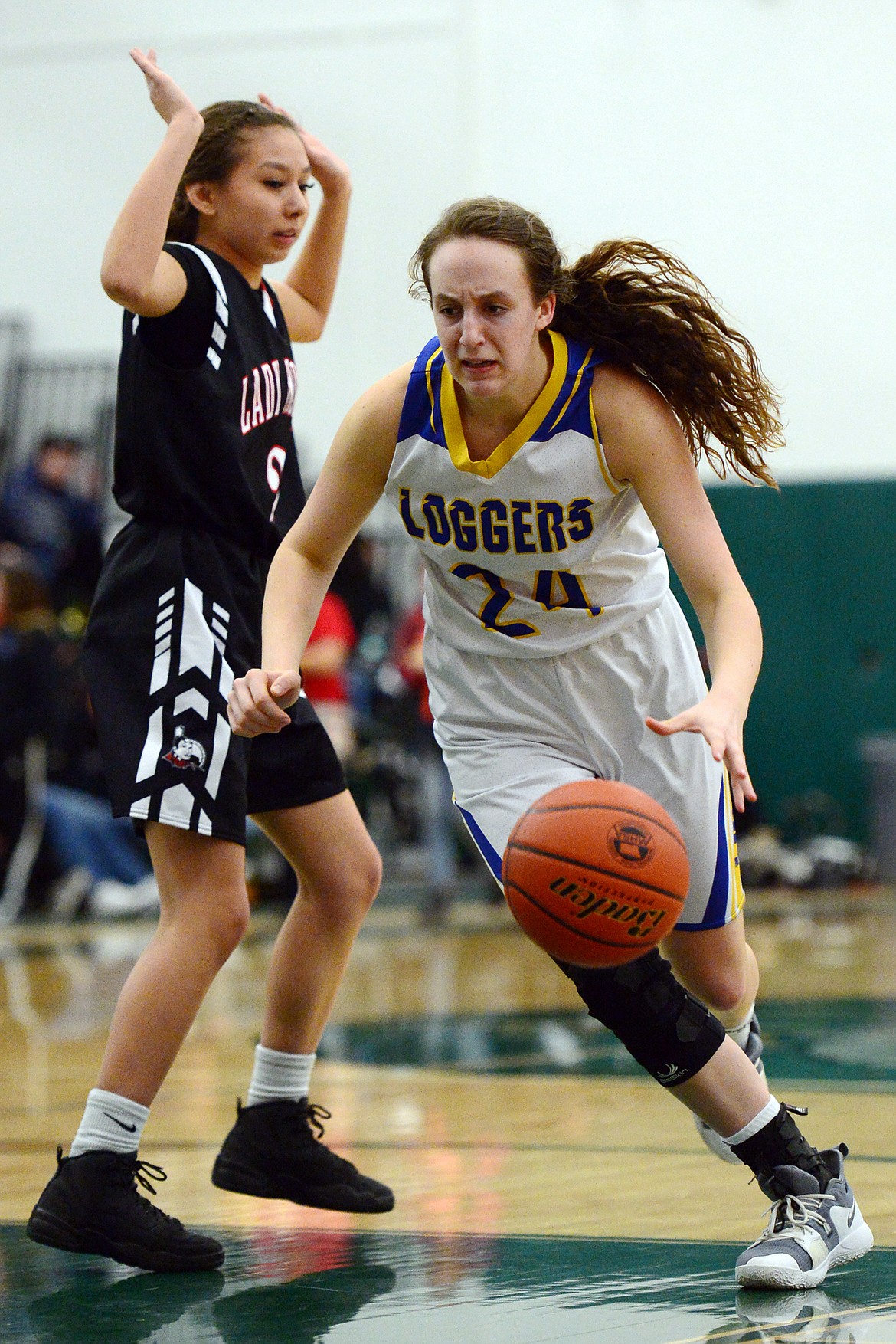 Libby's Jayden Winslow (24) drives to the basket around Browning's Chalissa Kipp (2) at Whitefish High School on Friday. (Casey Kreider/Daily Inter Lake)