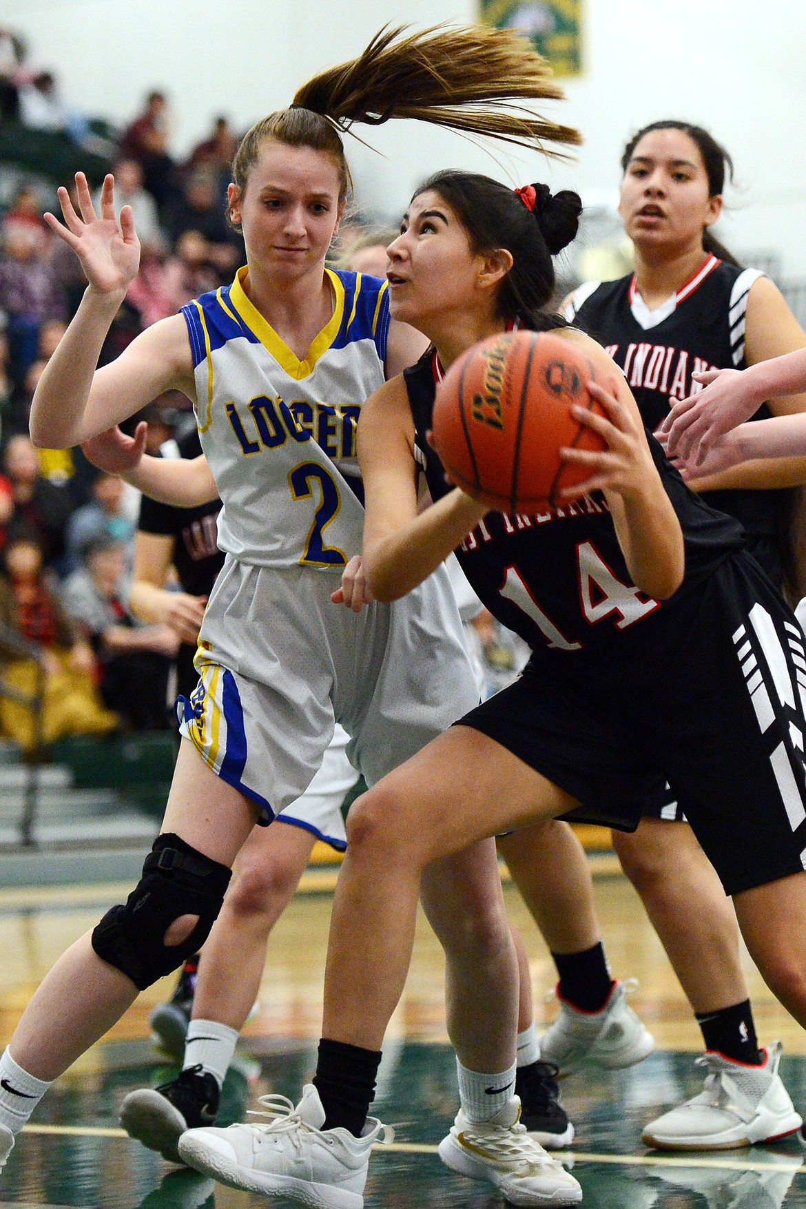 Browning's Kelsey Mad Plume (14) drives to the basket with Libby's Samantha Miller (22) defending at Whitefish High School on Friday. (Casey Kreider/Daily Inter Lake)