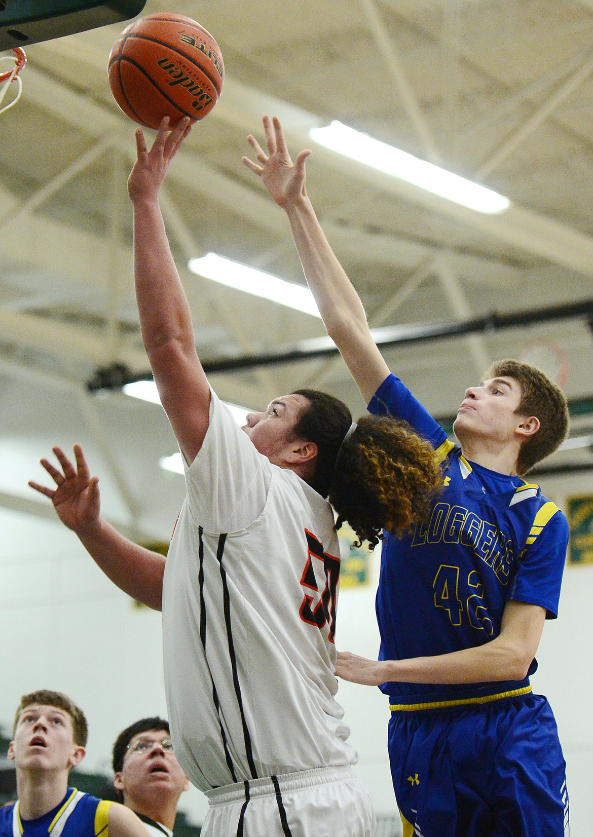 Ronan's Anthony Camel (50) drives to the basket in front of Libby's Keith Johnson (42) at Whitefish High School on Thursday. (Casey Kreider/Daily Inter Lake)