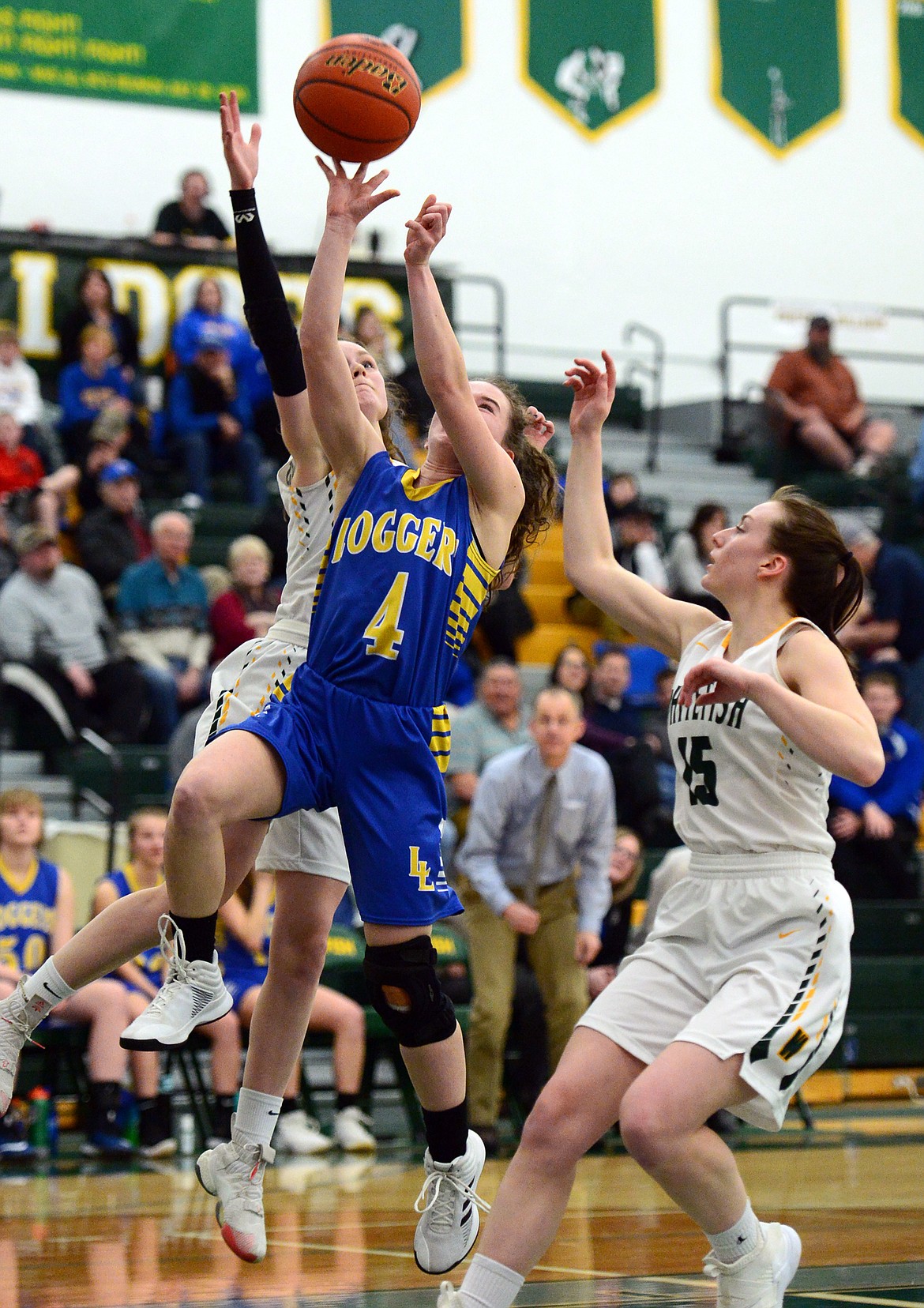 Libby's Emma Gruber (4) drives to the basket against Whitefish's Kaiah Moore (2) and Payton Kastella (15) at Whitefish High School on Thursday. (Casey Kreider/Daily Inter Lake)