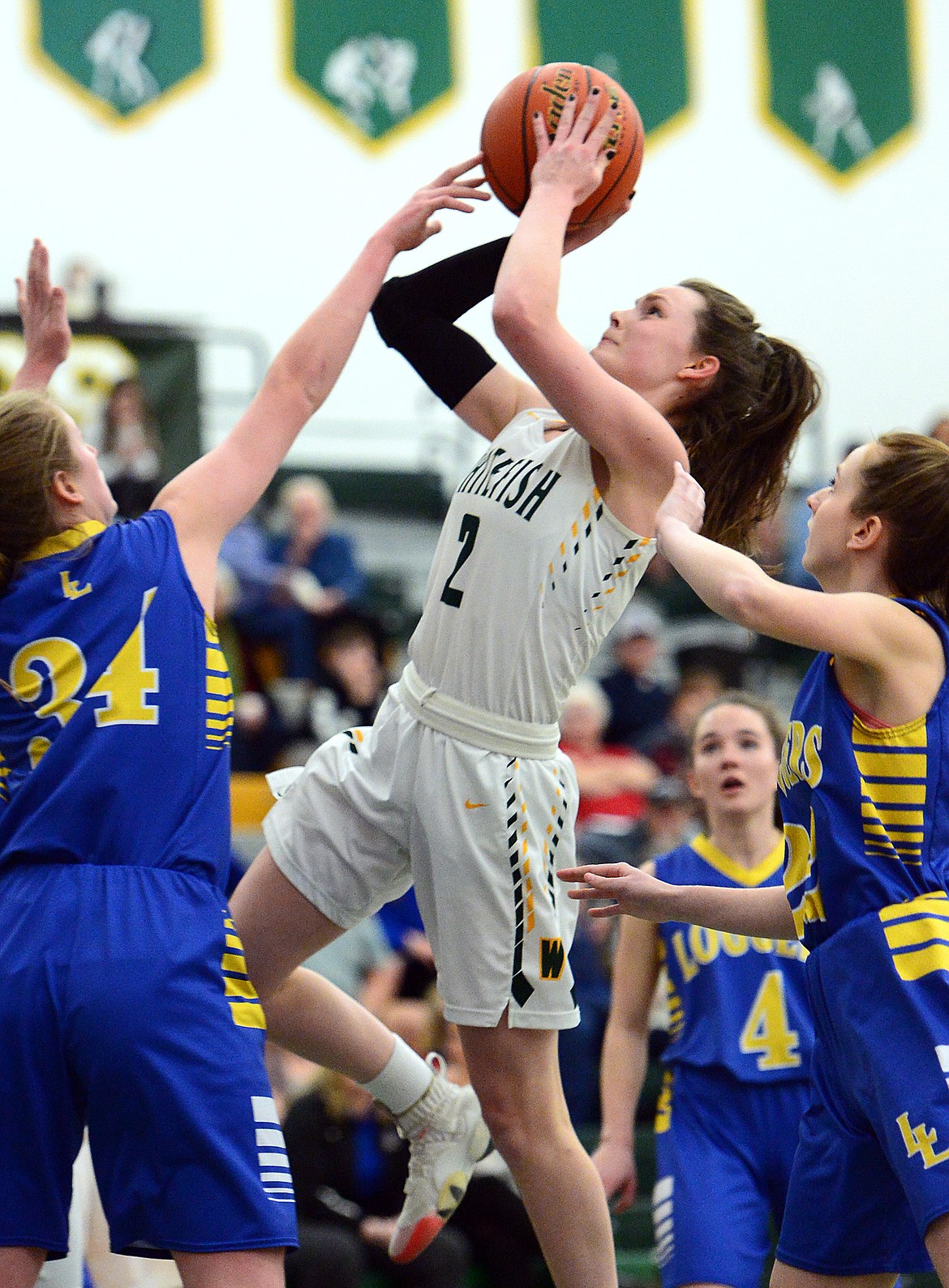 Whitefish's Kaiah Moore (2) drives to the basket between Libby defenders McKenzie Proffitt (34) and Jayden Winslow (24) at Whitefish High School on Thursday. (Casey Kreider/Daily Inter Lake)