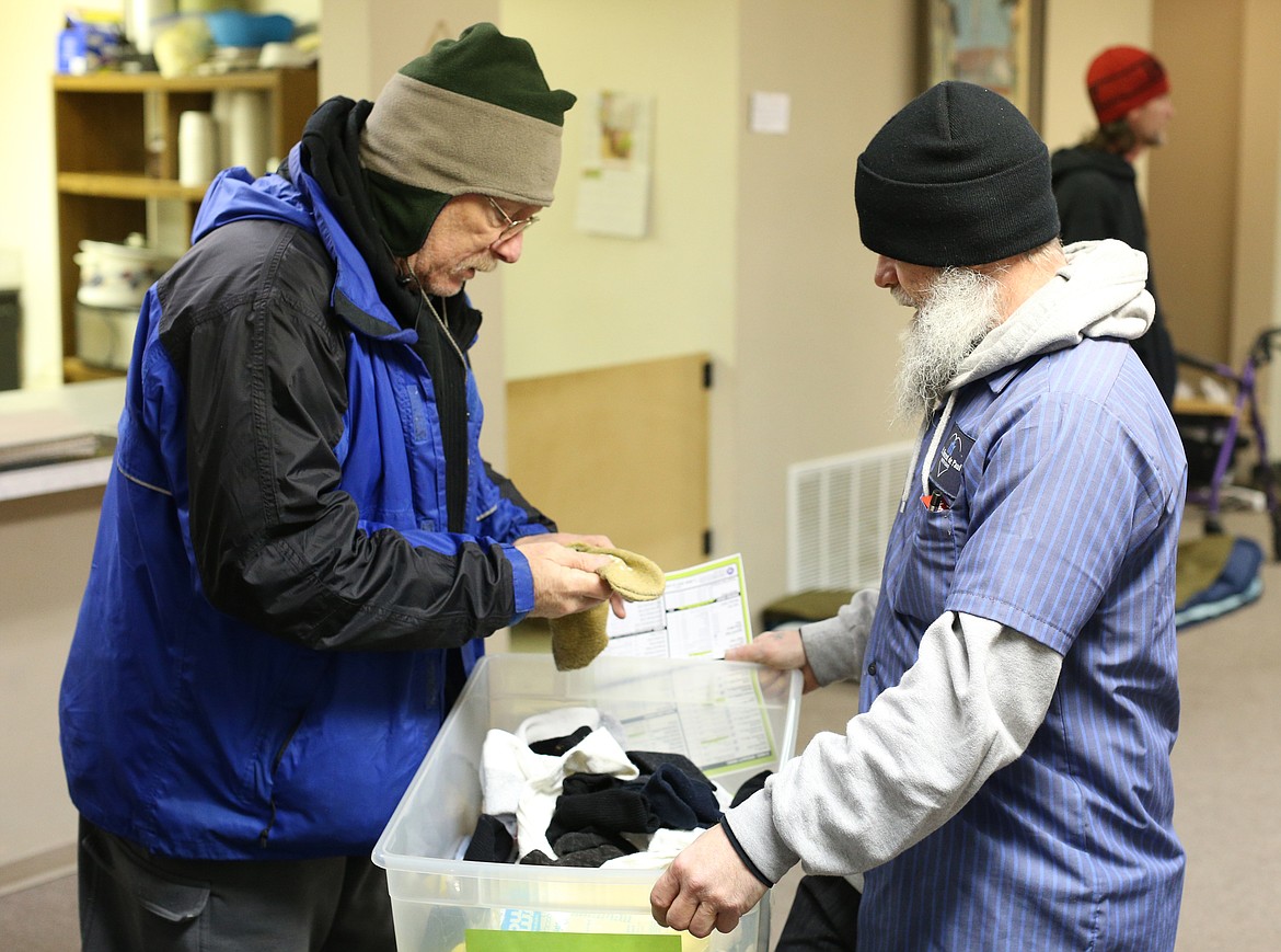 St. Vincent de Paul Warming Center manager Wayne Elliott, right, distributes socks to Dave Smith and others inside of the center last week. (LOREN BENOIT/Press)