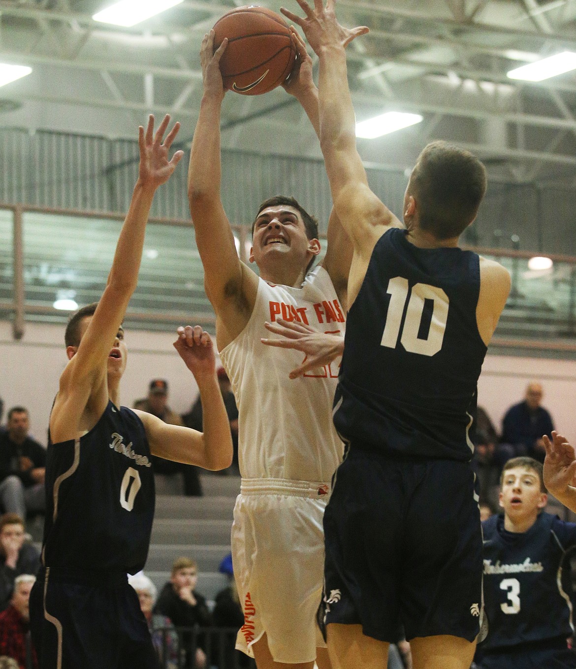 Post Falls' Gavven Desjarlais goes for a layup while defended by Lake City's Josh Stellflug (0) and Nathan Spellman (10) during a game in January. (LOREN BENOIT/Press)