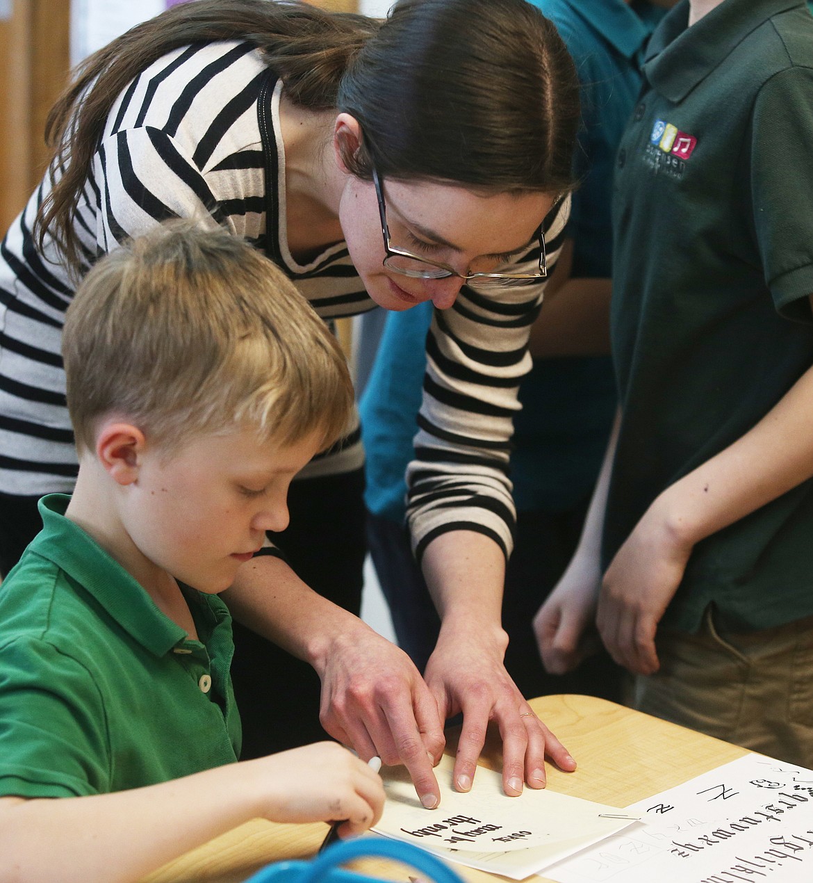 Artist-in-residence Hannah Charleton helps fourth grade student Bridger Demoe with his medieval manuscript Tuesday at Sorensen Magnet School. (LOREN BENOIT/Press)