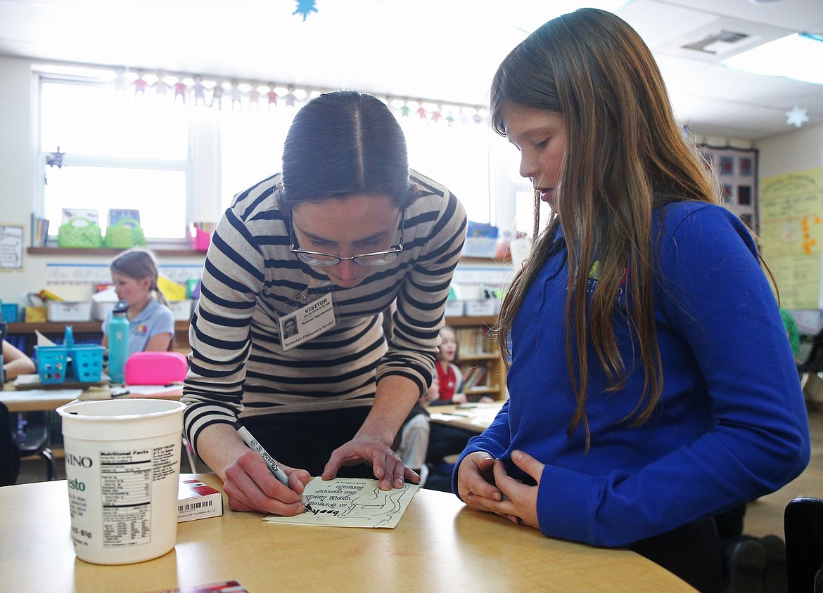 Artist-in-residence Hannah Charleton helps Abby Price fill in her student manuscript Tuesday afternoon at Sorensen Magnet School. In Charleton's workshop, she explained the history of art during the middle ages, as well as how books were made prior to the printing press. (LOREN BENOIT/Press)