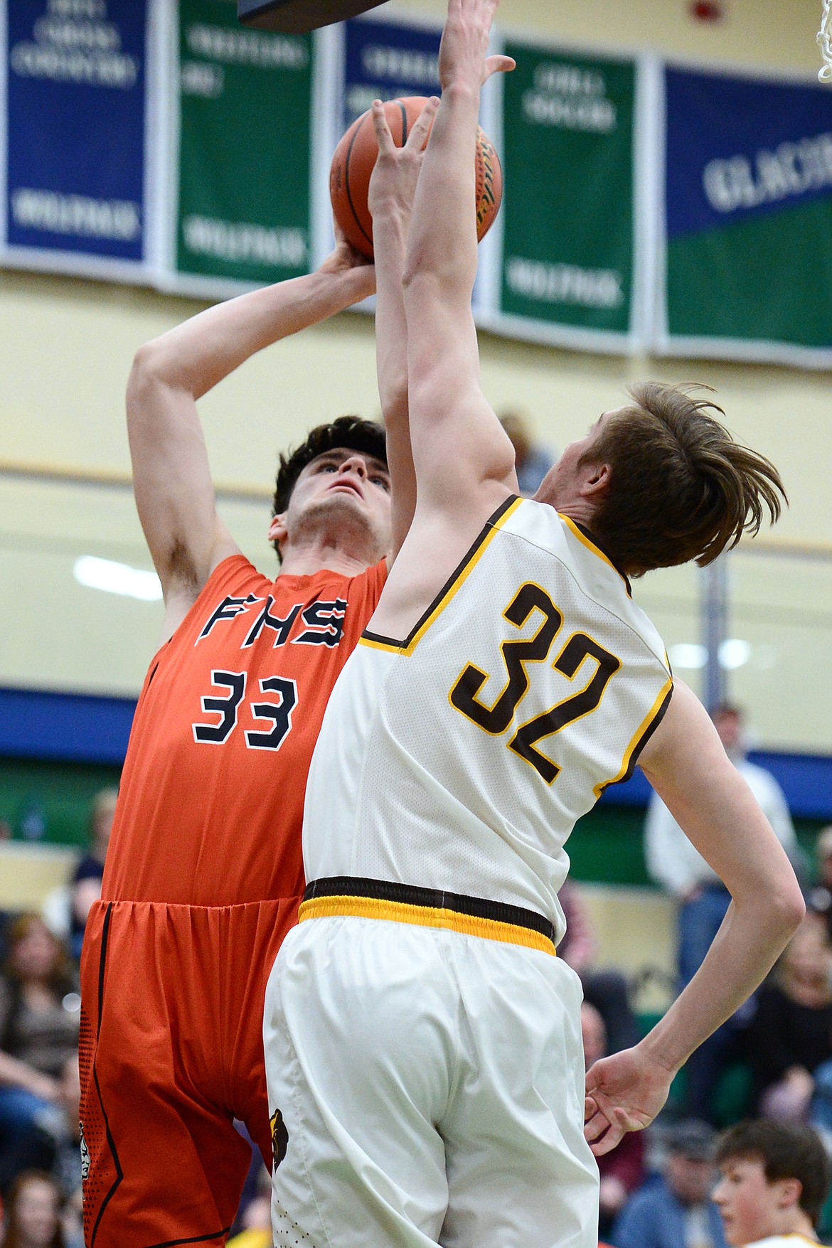 Flathead's Gabe Adams (33) powers to the hoop against Helena Capital's Shane Haller (32) during Western AA Divisional play at Glacier High School on Thursday. (Casey Kreider/Daily Inter Lake)