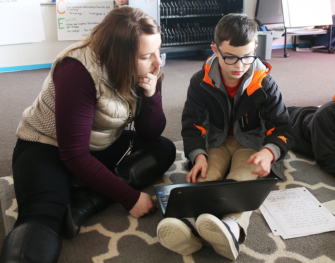 Fourth grade teacher Jessica Novak helps Kaden Stricklen on his persuasive letter to customers on how they should buy their class' fresh greens grown at Northwest Expedition Academy. (LOREN BENOIT/Press)