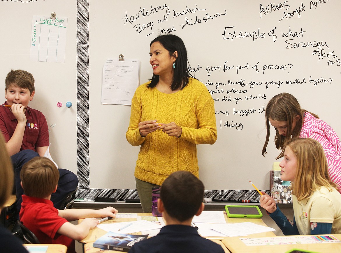 Artist-in-residence Christina Lucky, owner of Lucky Monkey, listens to a student explain a marketing idea Thursday at Sorensen Magnet School. Students broke into teams to develop Earth-environmental-themed designs that they&#146;ll create and print on recyclable bags. (LOREN BENOIT/Press)