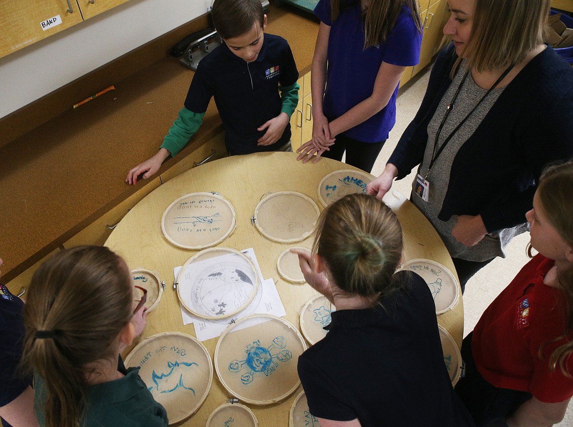 Fifth-grade students gather around a table and view Earth-environmental-themed designs made during class Thursday morning at Sorensen Magnet School. (LOREN BENOIT/Press)