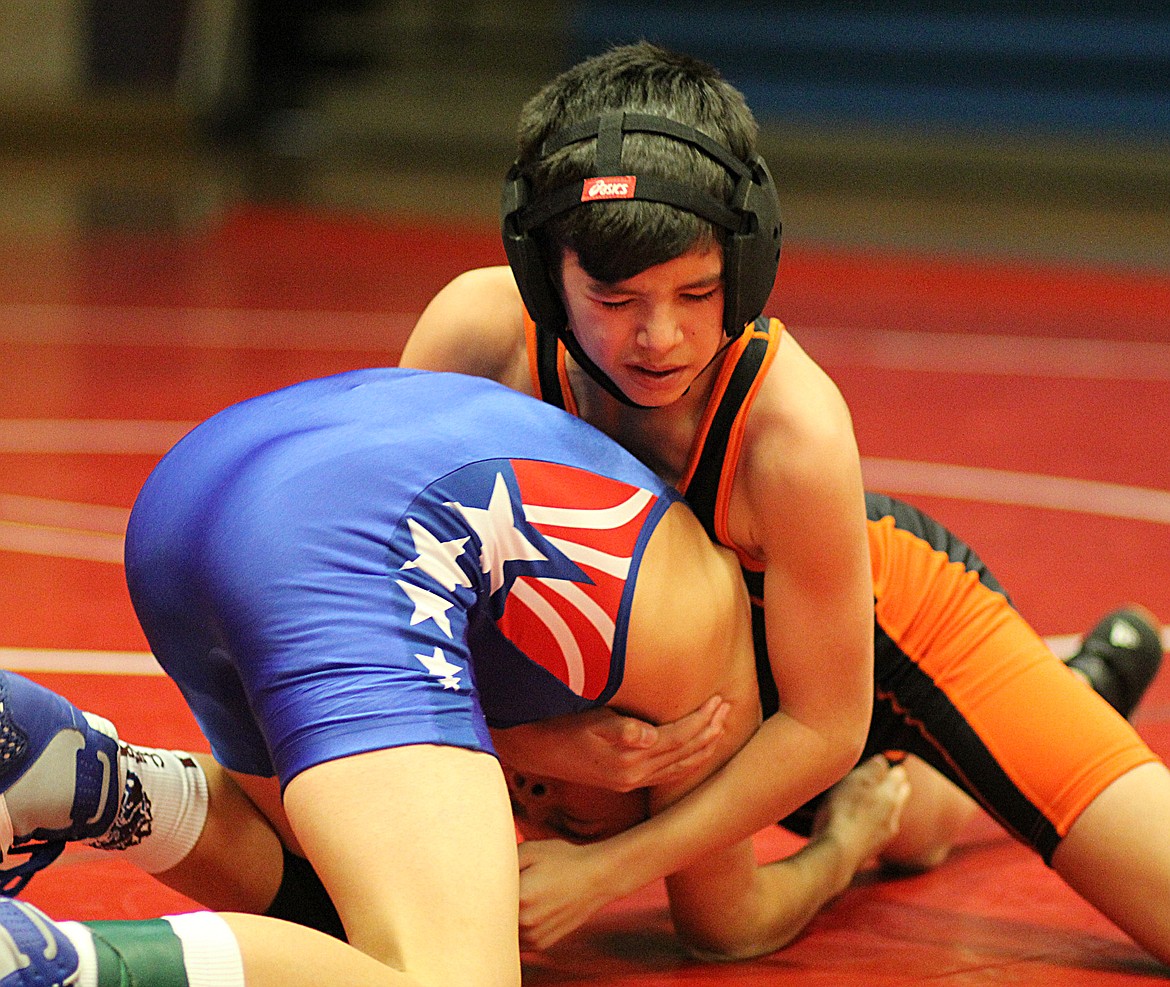 PLAINS/HOT SPRINGS grappler Gunner Gannarelli (orange and black singlet) gets a grip on Lucas Kovalsky of Clark Fork during the Superior Mixer last Thursday. (Kathleen Woodford photos/Mineral Independent)