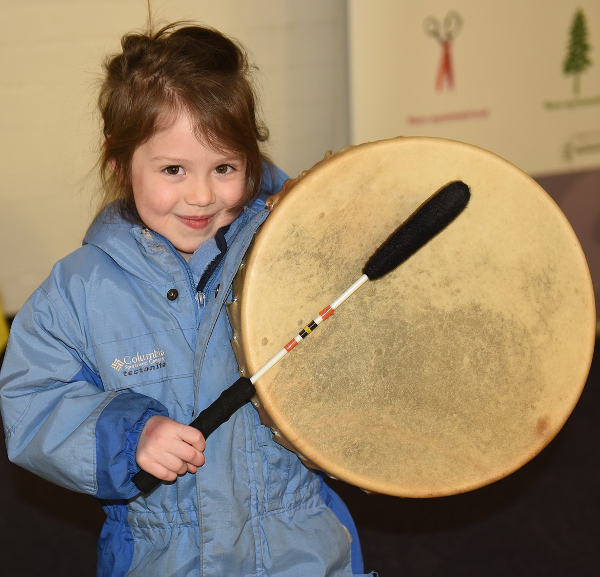 ROXY ROWE, who attends Cherry Valley Elementary Head Start, pounds out a tune on a native drum during the STEAM activity at Polson High School. Students in the SpectrUM program at UM in Missoula brought many props that were intriguing to youngsters in the Polson School District and State Tribal Education Partnership Program event.