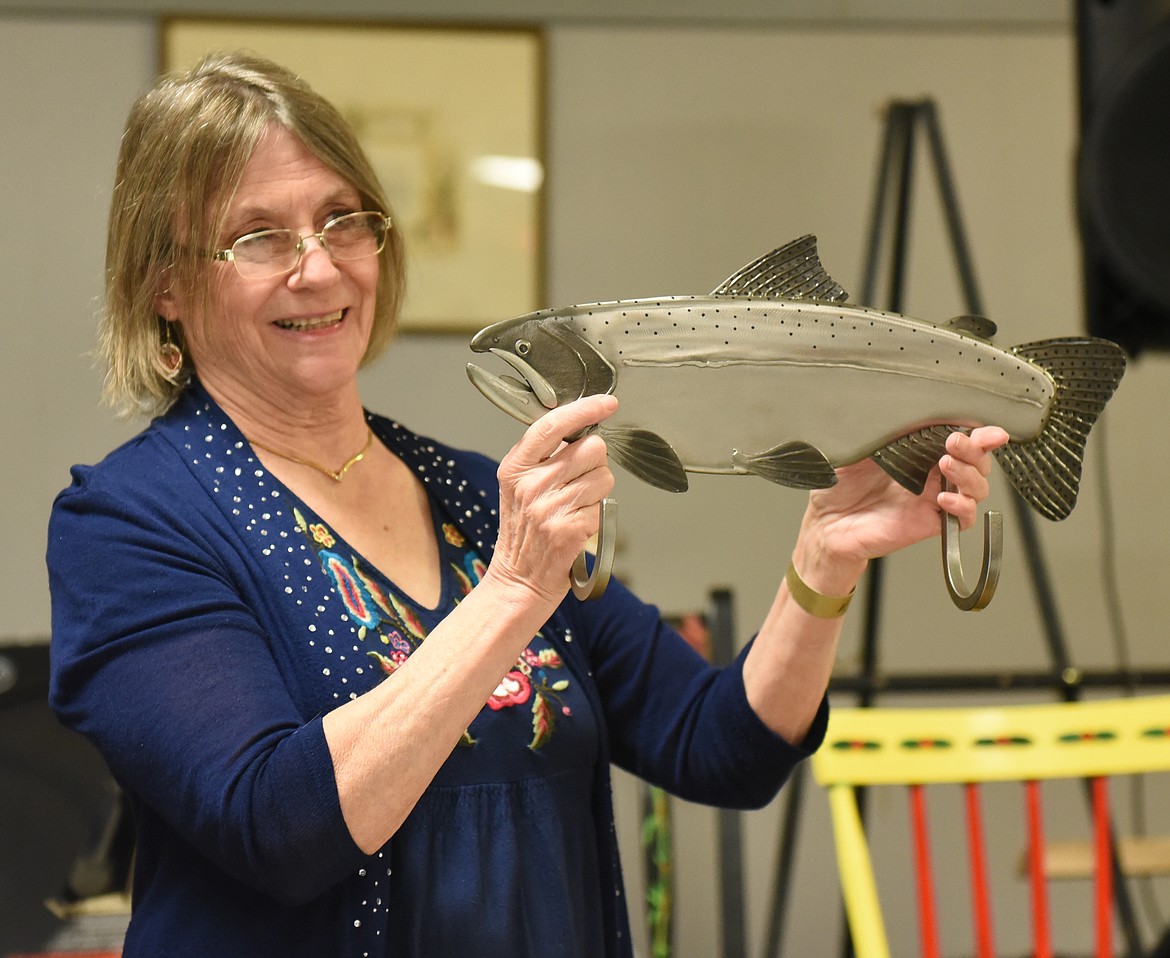 SUSAN EVANS shows a stainless steel fish that serves as a coat or hat rack during the live auction at the Winter Fiesta at the Polson Elks Lodge. Top bid on the stunning fish was $45. Evans said Soup&#146;s On is a community-wide volunteer effort, and $6,500 was raised for the program and about 80 people attended the Winter Fiesta.