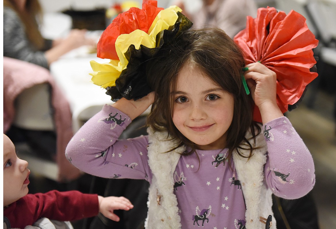 ALTHEA CHESARU, 5, wears flowers in her hair during the Winter Fiesta benefit at the Polson Elks Lodge last Saturday evening. Her 6-month-old brother Evren is mesmerized by Althea and the flowers. The Winter Fiesta, in its 10th year, was a benefit to celebrate more than 89,000 meals served at the Soup&#146;s On and Family Table in Polson. Soup&#146;s On is featured each Wednesday and Thursday from 11 a.m. to 1 p.m. at the Wander Inn, at 101 7th Ave. W. in Polson. (Joe Sova photos/Lake County Leader)