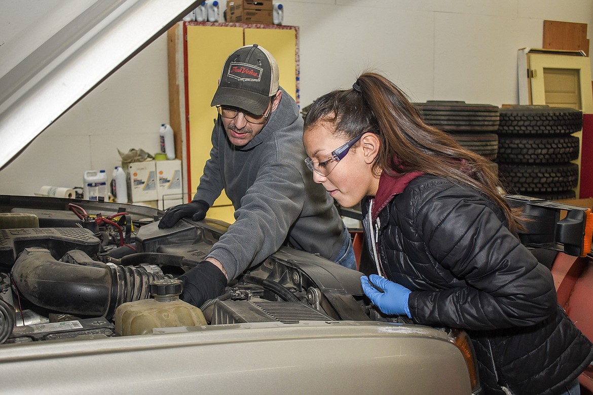 Keith Haggerty works with Troy student worker Izzy Ramirez as they do maintenance on one of the school’s fleet vehicles Feb. 5. (Ben Kibbey/The Western News)