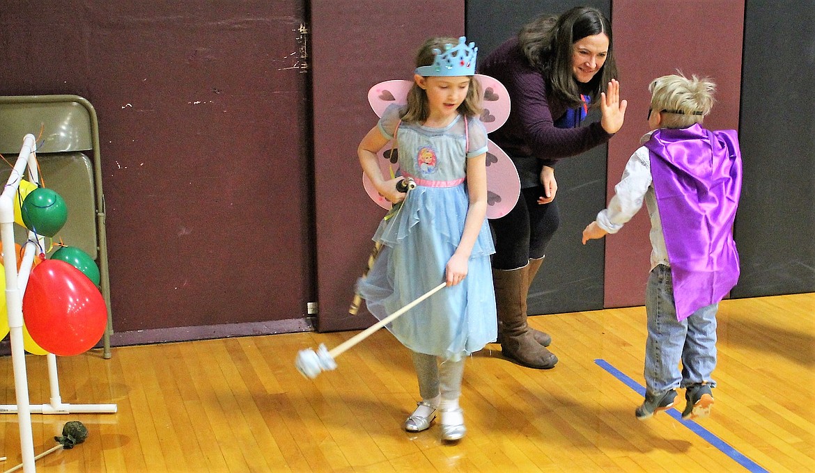 Ava Crittendon (7) practices her bow and arrow skills at the Super Hero Princess Party in Alberton, while three-year-old Gus Rausch get a high-five from mom, Richae.
 (Kathleen Woodford/Mineral Independent).