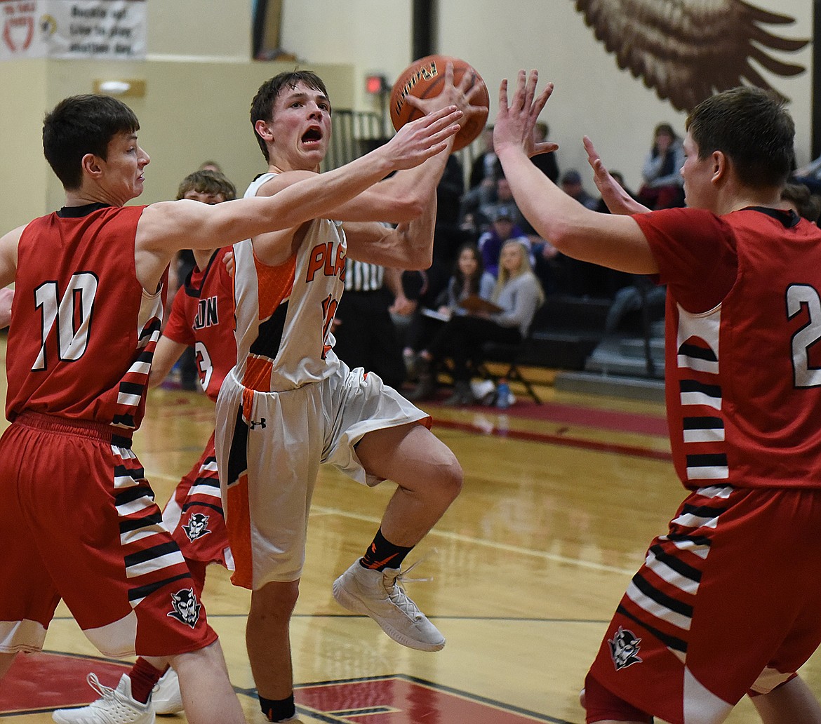 PLAINS JUNIOR Treydon Brouillette goes to the basket between Noxon defenders Jeriko Smith-Roach (10) and Rylan Weltz (21) in a loser-out game Saturday at the 14C District Tournament. The Horsemen pulled away for a 40-32 win. (Joe Sova/Clark Fork Valley Press)