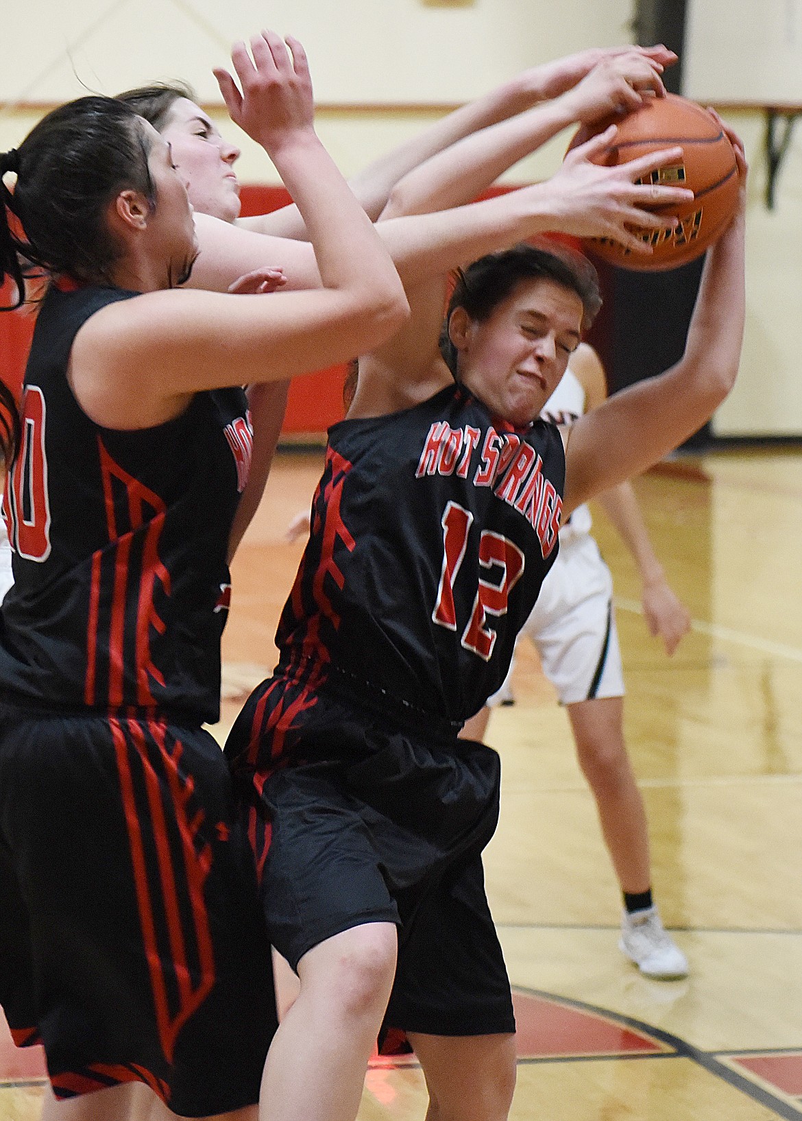 HOT SPRINGS junior Sydney Jackson (12) wrestles the ball away from a Plains player during Saturday&#146;s loser-out game in the 14C District Tournament. Plains stayed alive with a 52-41 win. (Joe Sova/Clark Fork Valley Press)