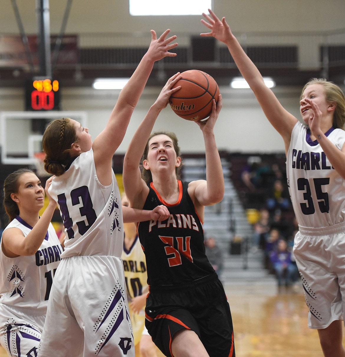 PLAINS SENIOR Rachel Huenink (34) takes the ball to the hoop between Charlo defenders Allie Delaney (43) and Carlee Fryberger (35) during semifinals action at the 14C District Tournament at SKC in Pablo. Charlo edged the Trotters, 37-33. (Joe Sova/Clark Fork Valley Press)