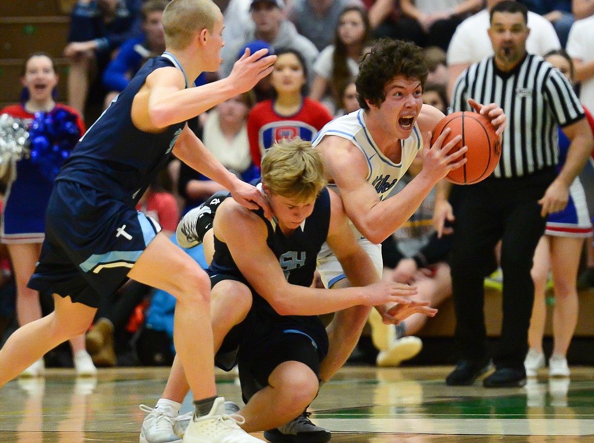 Bigfork's Randy Stultz fights for a loose ball with Loyola's Jacob Hollenback (5), left, and Ryan Tirrell (2) in the State Class B boys' basketball championship at the Belgrade Special Events Center in Belgrade on Friday. (Casey Kreider/Daily Inter Lake)