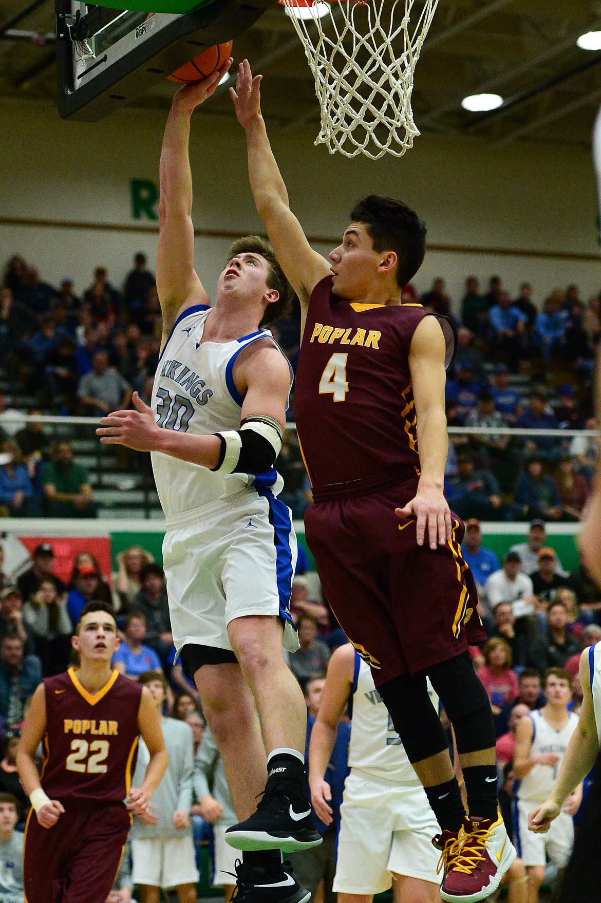 Bigfork's Logan Gilliard (30) drives to the hoop against Poplar's Kenny Smoker (4) in the State Class B Boys' Basketball Tournament at the Belgrade Special Events Center in Belgrade on Thursday. (Casey Kreider/Daily Inter Lake)