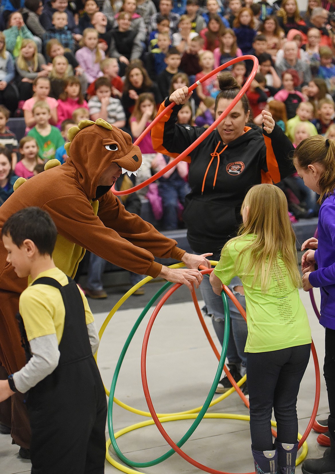 TEAMS OF Plains students and teachers raced to construct a hula hut made of hula hoops during the I Love to Read assembly last Friday in the school gym. Pictured from left are Cage Tuma, &#147;dinosaur&#148; Casey Thompson, Holly Blood, Tia Bellinger and Macey Malmend. Bleachers full of kindergarden- through sixth-grade students are in the background. (Joe Sova photos/Clark Fork Valley Press)