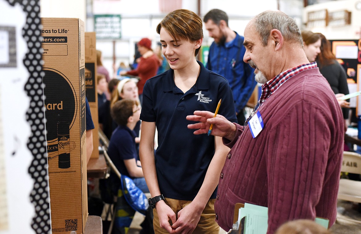Haden Graaff, a seventh-grader at Trinity Lutheran, presents his science fair project, which involved creating two Gauss Rifles, to judge Karl Sorenson on Thursday at the Flathead County Fairgrounds. Graaff explained that the rifle shoots marbles using two magnets which repel each other. (Brenda Ahearn/Daily Inter Lake)