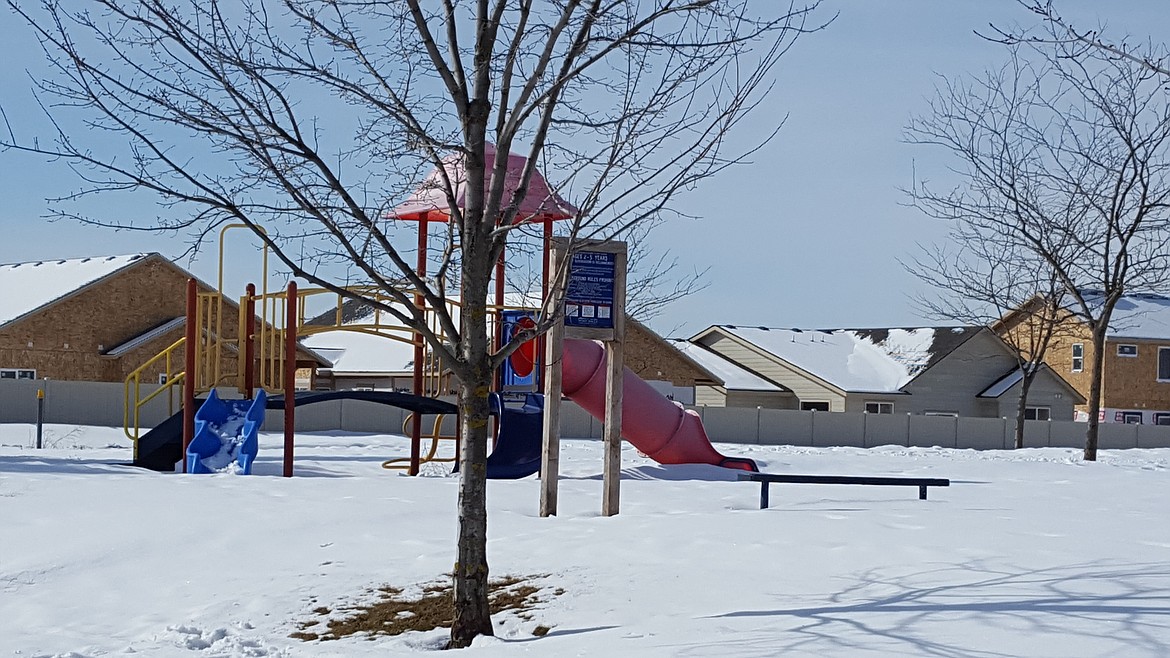 A play structure and park area in the original Woodbridge neighborhood, with construction in Woodbridge South seen behind it.