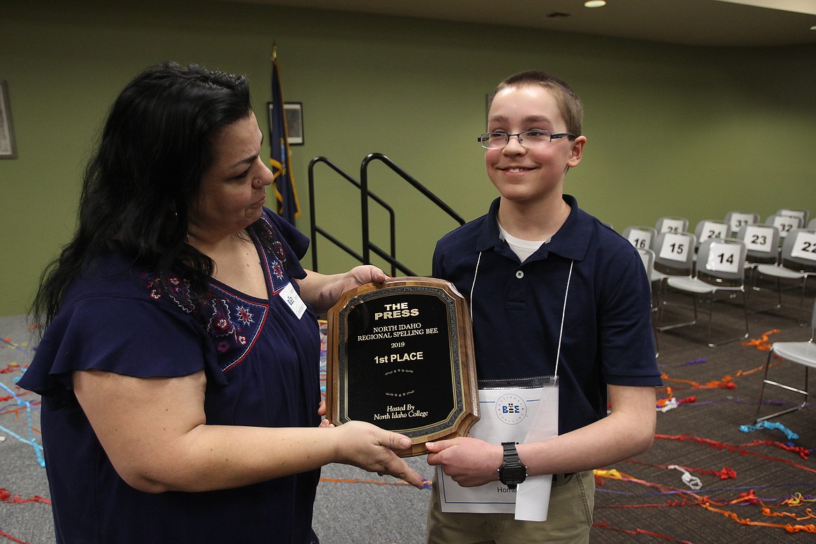 Three-time North Idaho Spelling Bee winner Joseph Moran accepts a plaque from bee coordinator Kathryn Meyer after he claimed another victory on Saturday. (DEVIN WEEKS/Press)