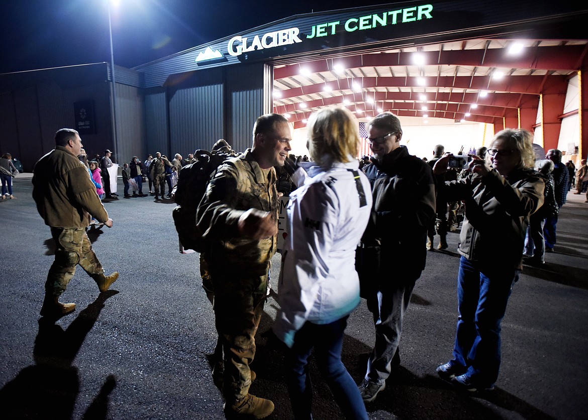Battalion Commander Lt. Col. Mike Beck reaches out to hug his wife Jeri as he and the 495th Combat Sustainment Support Battalion arrive at the Glacier Jet Center on Saturday night, March 16.(Brenda Ahearn/Daily Inter Lake)