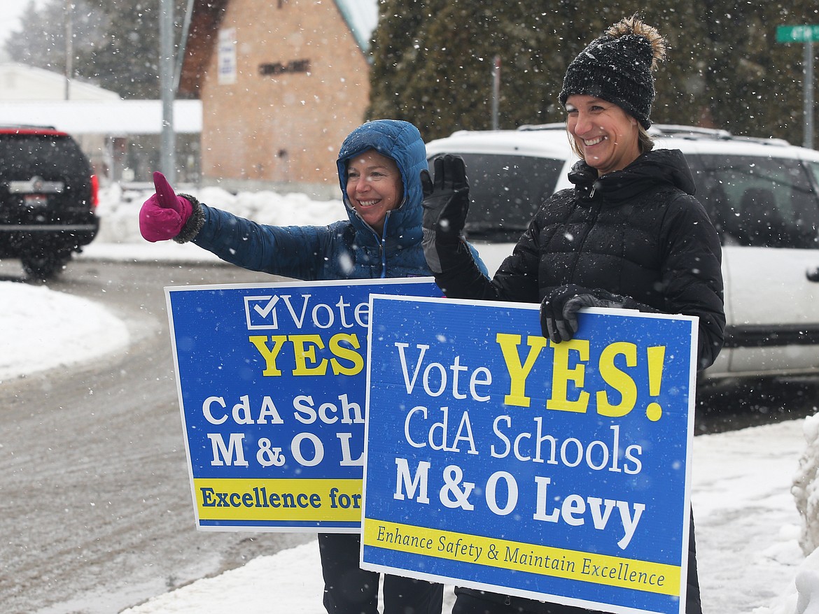 Coeur d&#146;Alene School Board Trustee Lisa May, left, and Marnie Wilson, a parent, brave the weather and wave to drivers near the intersection of Hanley and Fourth Street in Dalton Gardens during Tuesday&#146;s election. (LOREN BENOIT/Press)