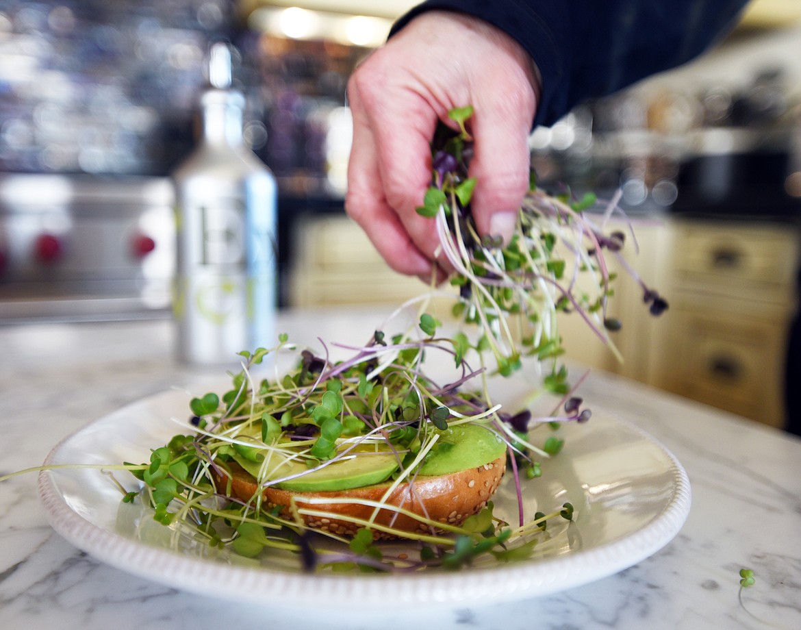 Susan Waite adds micrgreens to a toasted bagel with sliced avocado. People who grow their own microgreens don&#146;t use them sparingly because they are not such a precious commodity.
(Brenda Ahearn/Daily Inter Lake)