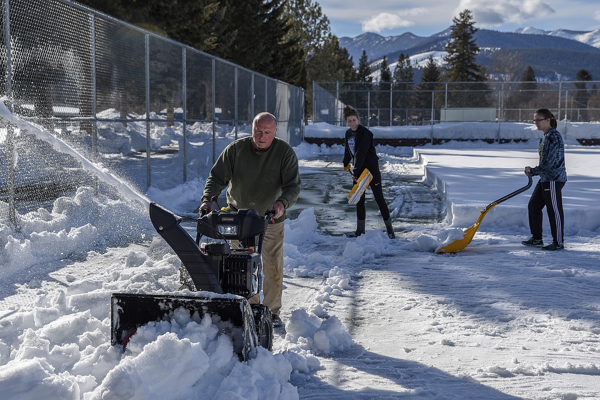 Elise Erickson and Ciera Lucas (background) shovel snow to the edge for assistant Coach Terry Oedewaldt to clear away with the snow blower Friday as the team cleared the courts. (Ben Kibbey/The Western News)