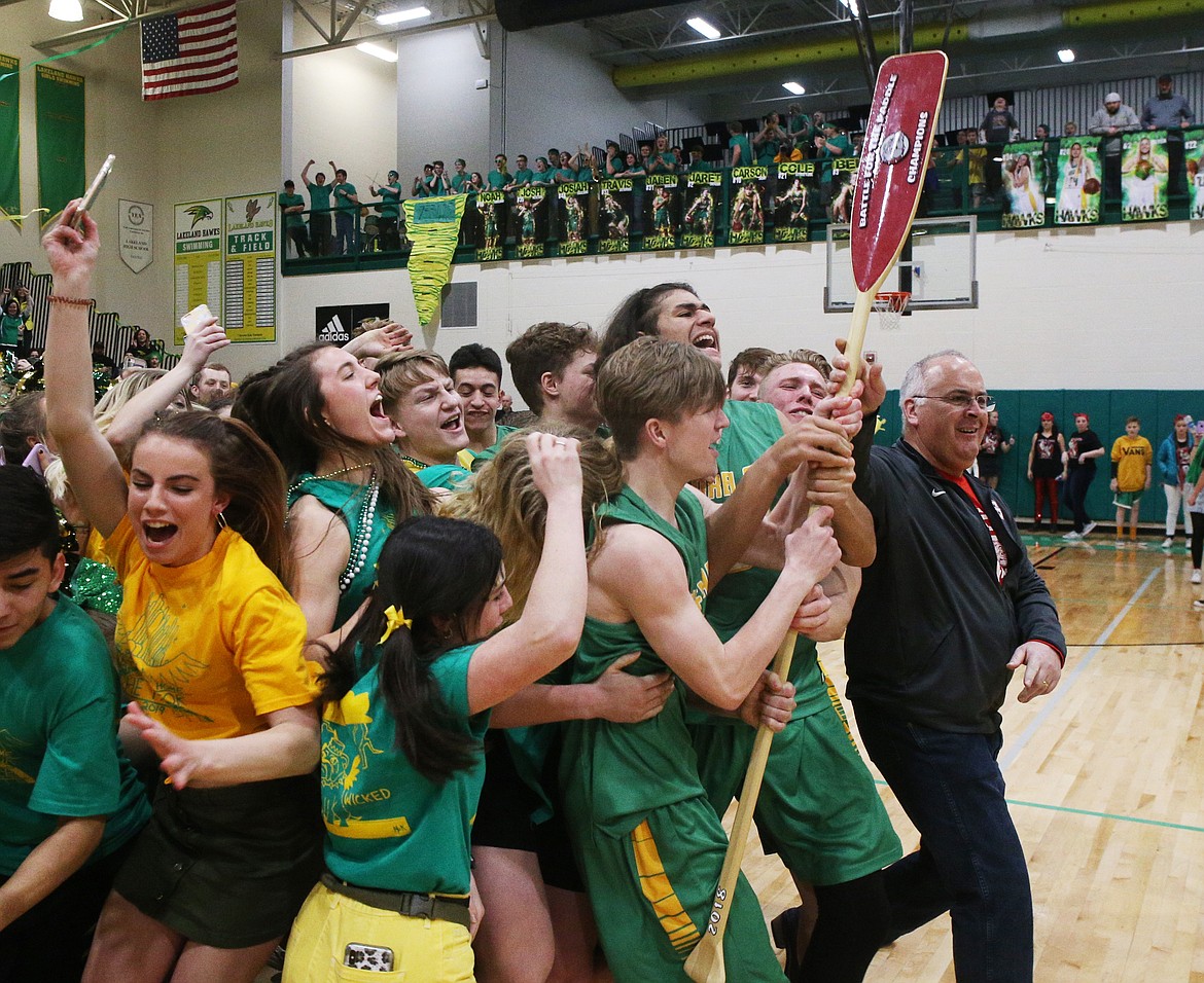 The Lakeland High School boys basketball team and students rush the court to take back the paddle after defeating Sandpoint in the Battle for the Paddle in Rathdrum.