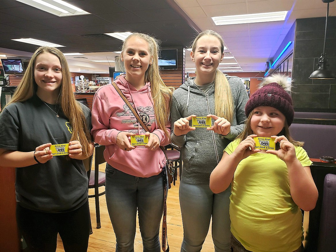 &#147;Arrive Alive! Don&#146;t Drink &amp; Drive&#148; stickers were put on bags, cups and containers to remind drivers to drive sober. The stickers were put on the items by area students, including Baylee Pruitt (far left), Emma Hill, Kylee Thompson and Bella Cheesman (far right) from St. Regis School last weekend. (Photo courtesy of Tyler Cheesman)