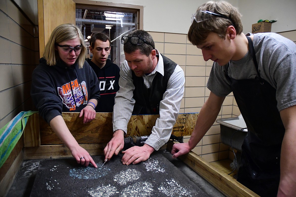 CFHS industrial arts teacher Jeff Remiker (center) work with students, from left, Kaila Belston, Austin Dull and Zack Pletcher Monday. The CFHS construction class will be building a cabins for Glacier National Park beginning next school year as part of the &quot;School to Park&quot; program. (Jeremy Weber photo)