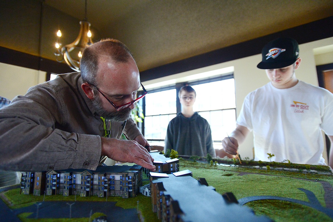 Lance Fahrney, president of The Woodlands, arranges an architectural model of the future residential development with high school freshman Micah Reeves and junior Eric Anderson, both students at Stillwater Christian School on Wednesday, March 20. (Casey Kreider/Daily Inter Lake)