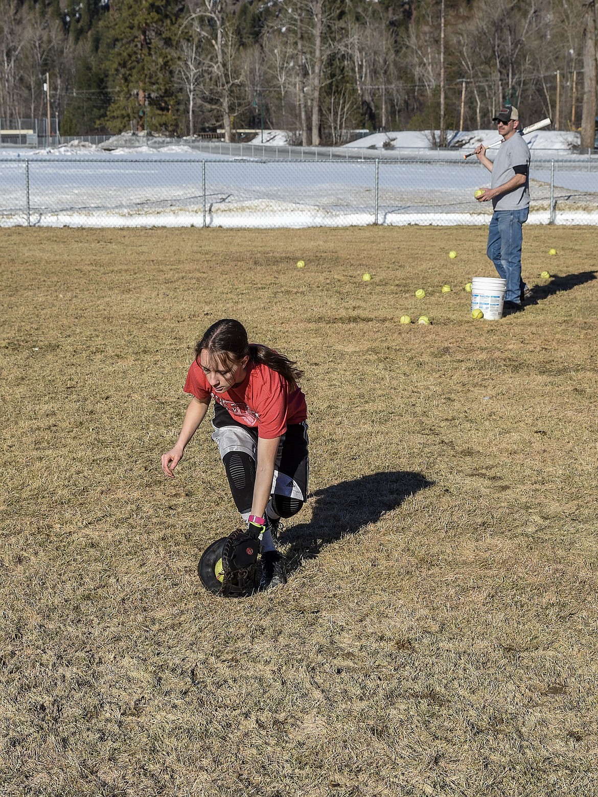 Troy senior Kaylee Tunison grabs a grounder as Troy Head Coach Keith Haggerty gets ready to hit another ball during fielding practice at the Troy practice field March 18. (Ben Kibbey/The Western News)