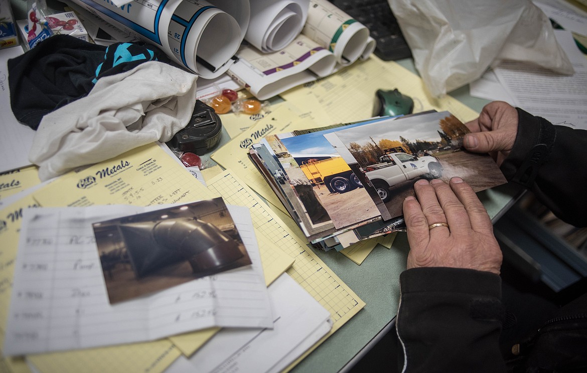 LeRoy Thom, owner of Montana Machine &amp; Fabrication, flips through photos of projects he has worked on over the years, Friday in his office in Libby. (Luke Hollister/The Western News)