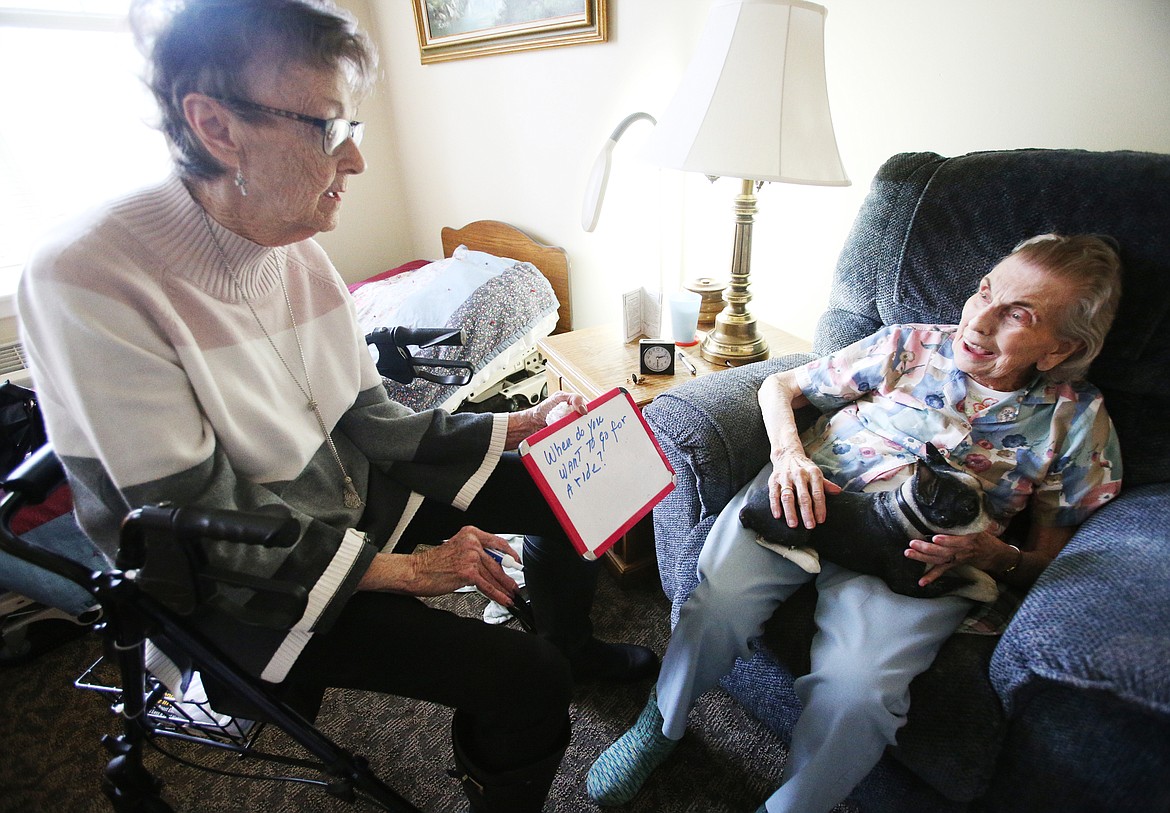 LOREN BENOIT/Press 
Senior Companion program volunteer Peggy Smith uses a white board to ask Orchard Ridge resident Fran Ellig, 103, about when she would like to go for a drive around town with her artificial dog Buster on Friday.