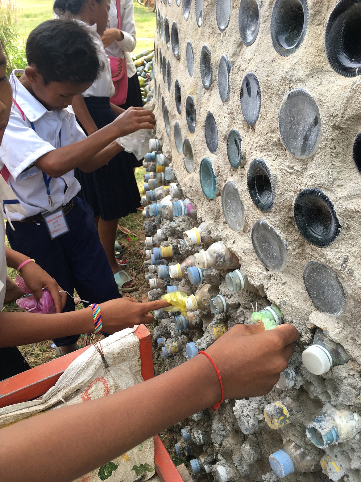 Students stuff plastic bags into plastic bottles used in building construction at the Red Road Foundation school campus in Cambodia.