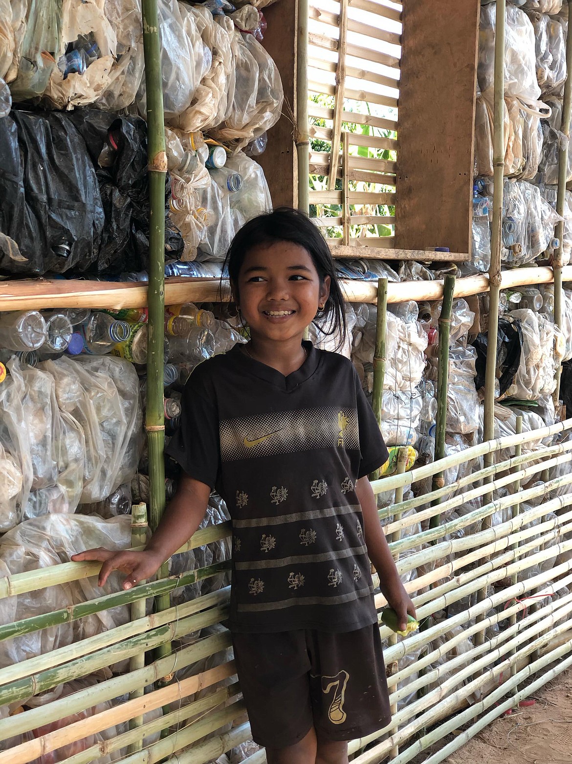 A Cambodian student is pictured with a bin of plastic that will be used in building construction at the Red Road Foundation&#146;s facilities in southern Cambodia.