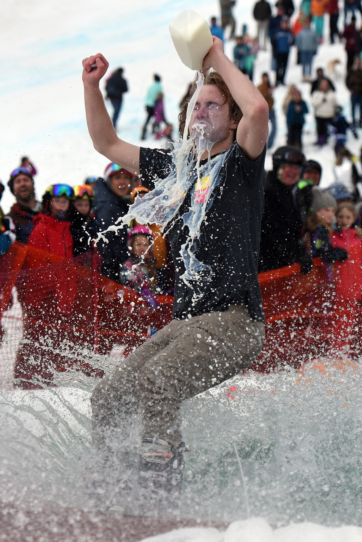 Shane Marcial skims across the pond while chugging a quart of milk during the 2019 Whitefish Pond Skim at Whitefish Mountain Resort on Saturday. (Casey Kreider/Daily Inter Lake)