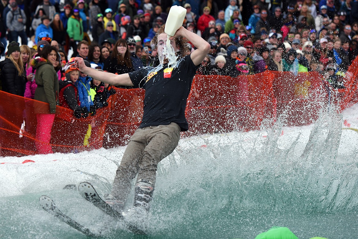 Shane Marcial skims across the pond while chugging a quart of milk during the 2019 Whitefish Pond Skim at Whitefish Mountain Resort on Saturday. (Casey Kreider/Daily Inter Lake)